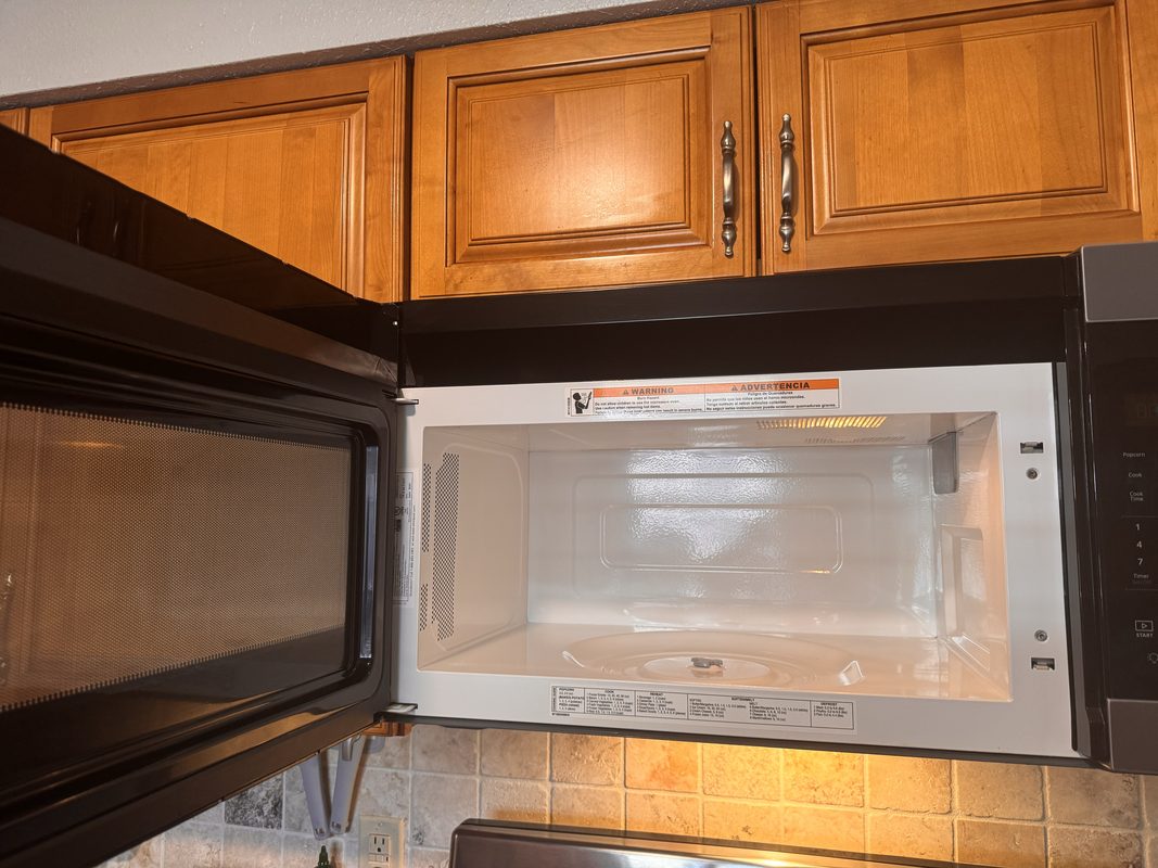 The same microwave after cleaning, with the cavity wiped down and the glass turntable taken out to be washed.
