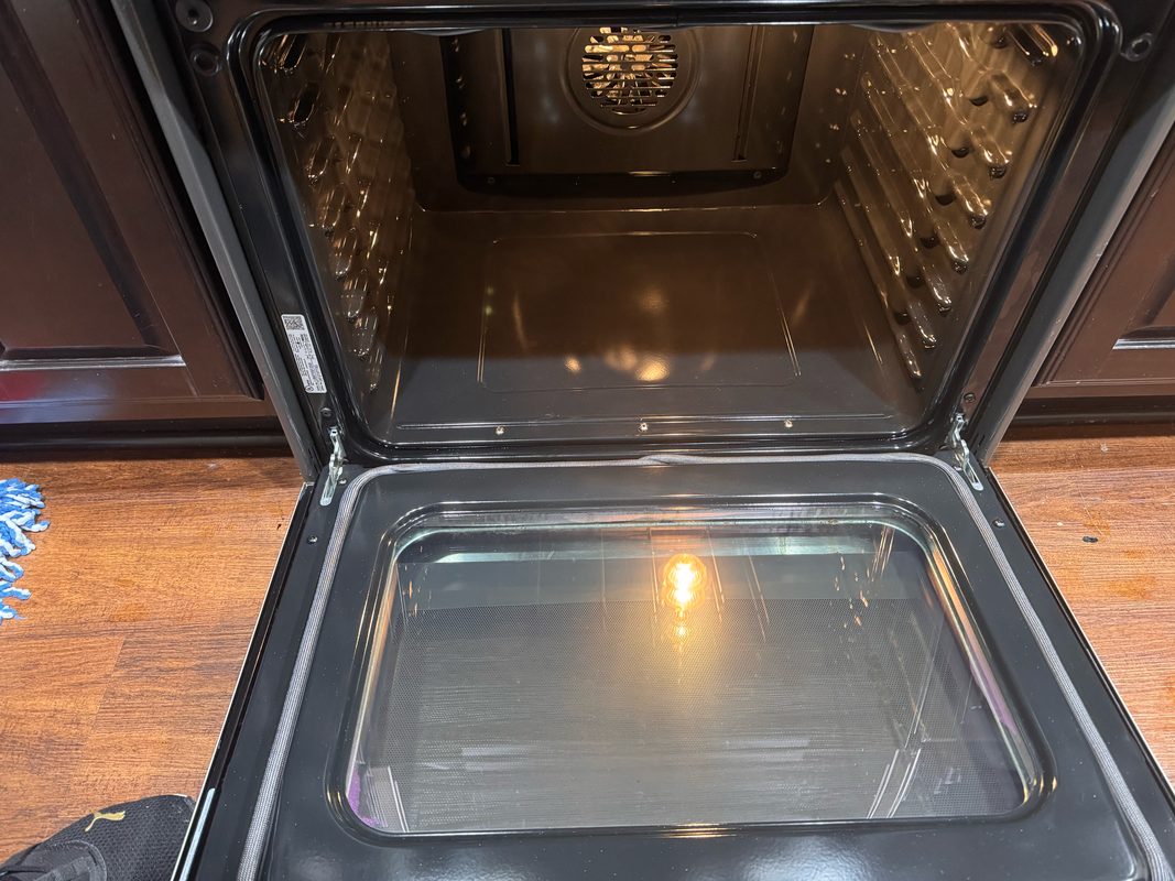 The same oven after cleaning, with clear door glass and the cavity walls and floor wiped down.