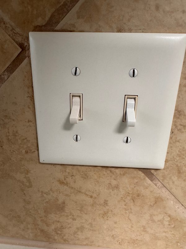 The same switch plate after cleaning, seen a little closer, white again with both toggles clean.