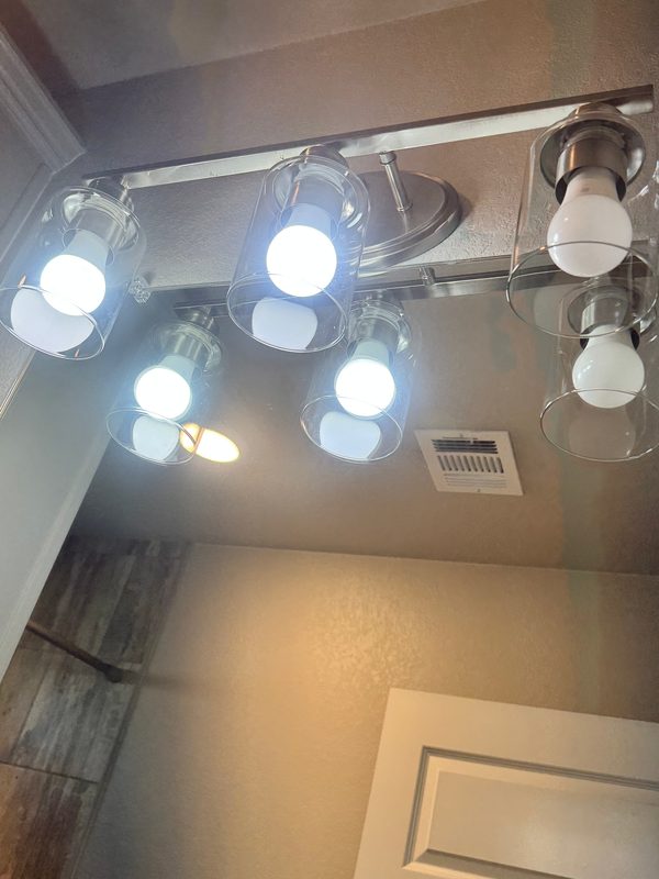 The same vanity light from the same spot after cleaning, its glass shades clear.